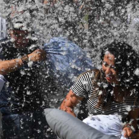 Feathers fly as participants attack each other with pillows during an International Pillow Fight Day event at Pershing Square in Los Angeles, California on April 1, 2017. / AFP PHOTO / Mark RALSTONMARK RALSTON/AFP/Getty Images
